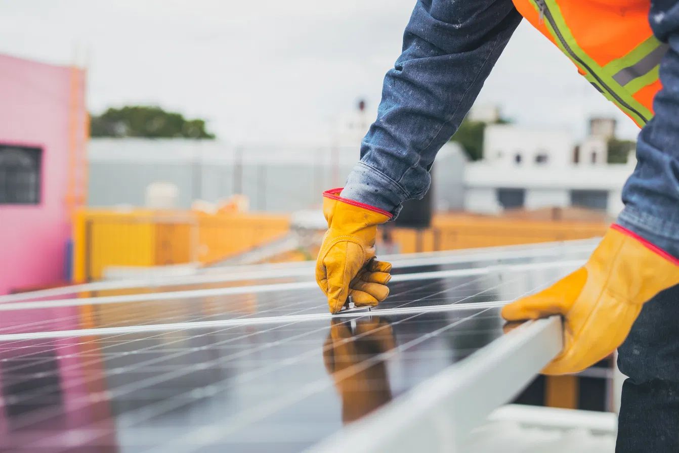 Installer's gloved hands fitting solar panels on a rooftop