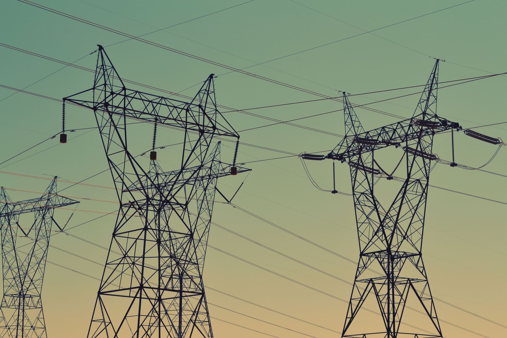 High-voltage electricity transmission pylons and power lines at dusk
